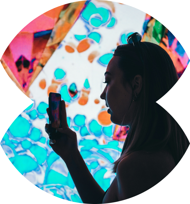 Frau mit Smartphone vor bunter Wand